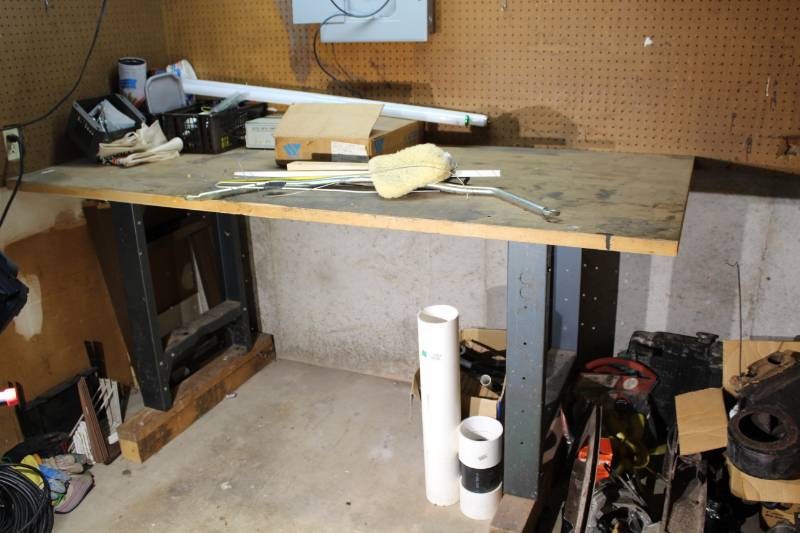 lot 1272 image: Large Heavy Workbench with Items on top Included, Welders Head wear, Red Hard Hat, 2 Metal shelves w Casters, Box of Philips fluorescent light bulbs