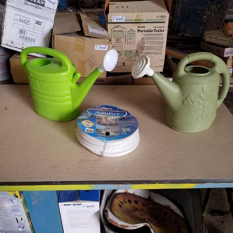 lot 7153 image: two watering cans - 1 is damaged and RV & Marine hose - 25 ft - 12 inch inside diameter