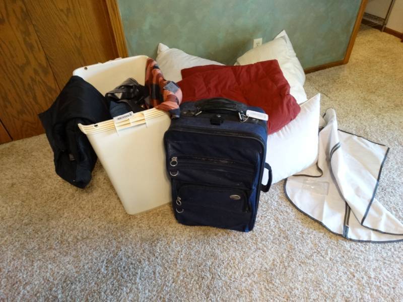 lot 399 image: Hamper, suitcase, clothes, and pillows.