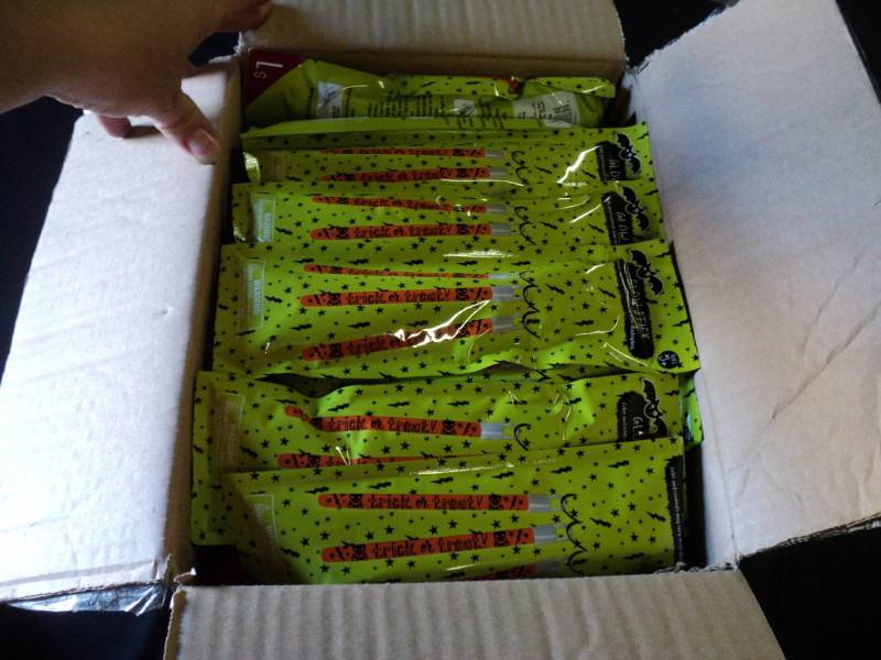 lot 9856 image: (1) case of Halloween Glowsticks, open box, approx (100) packages of (3) multi-colored glow sticks