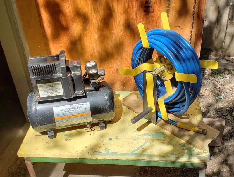 lot 1409 image: Central Pneumatic Air Compressor and Air Hose  Reel - Powers on