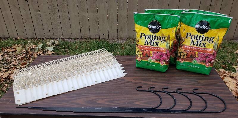 lot 2324 image: Lot of Garden Items - (16) Vintage White Plastic Edging (30 in. long) - some have slight damage, (5) Black Metal Shepherds Hooks (36 in. tall), and (4) Bags of Potting Mix
