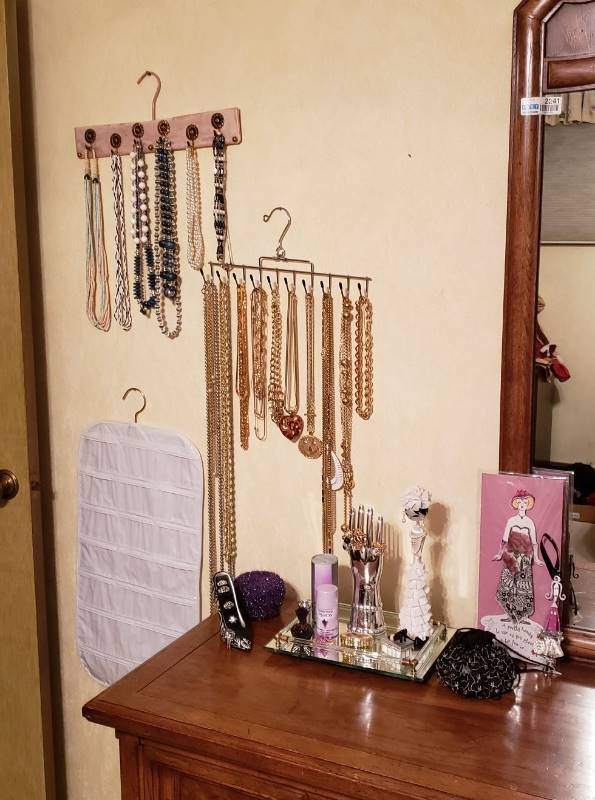 lot 2747 image: Lot of Jewelry- Necklaces on Wall Hangers, Perfumes, Rings, and Decor