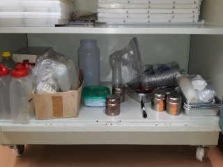lot 7133 image: Contents Inside Storage Cabinet, Poly Boards, Muffin Tins, Measuring Bottles, Calculators, Taste Spoons, etc.