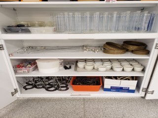 lot 7342 image: Contents of Shelving (Graduated Beakers, Sifters, Matches, Timers, Funnels)