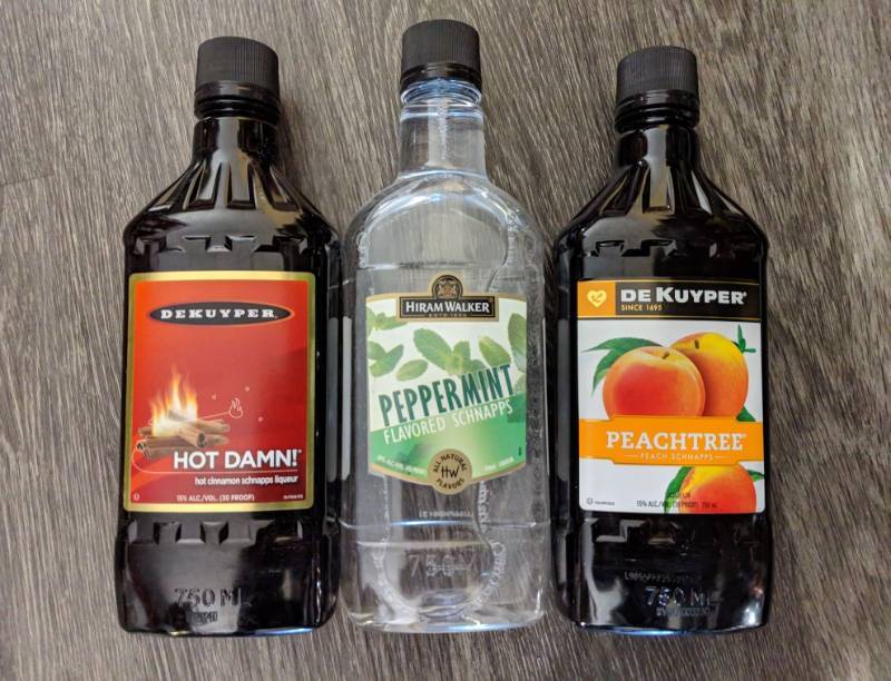 lot 9186 image: (3) 750mL Flavored Liqeuers, One Peppermint Flavored Schnapps 30 Perc Alc By Vol, One Hot Damn Schnapps Liqueur 15 Perc Alc By Vol, One Peachtree Peach Schnapps 15 Perc Alc By Vol