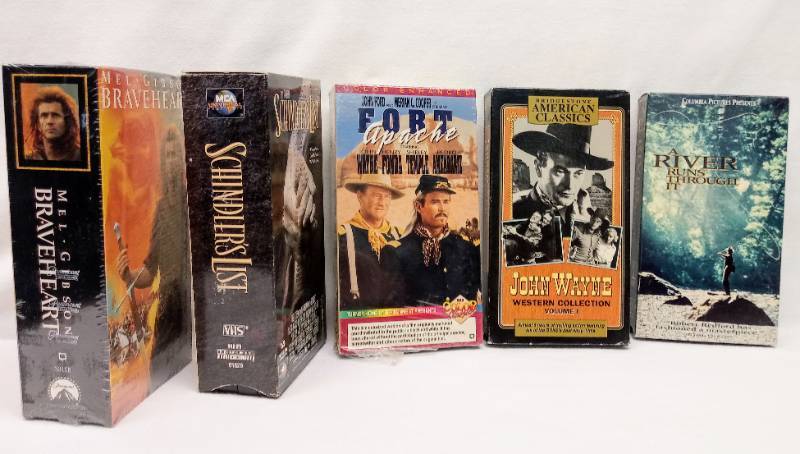 lot 5678 image: VHS Lot  John Wayne Movies, Schindlers List, Un-Opened Braveheart & A River Runs Through it
