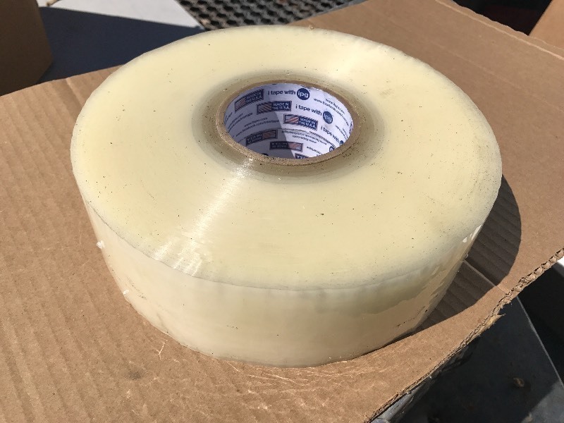 lot 407 image: Two large rolls of clear shipping tape each role 2.83 inches wide by 999 yards each row contains more tape and a standard case of small role