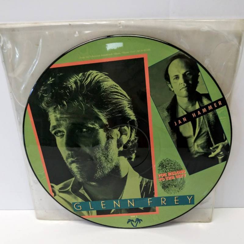 lot 9555 image: Vintage 12 Vinyl Miami Vice Picture Disc  2 Songs  Jan Hammer  Glenn Frey  Miami Vice Theme & You Belong To The City