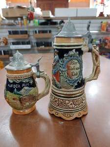 lot 2154 image: Lot of 2 West German Lidded Steins  Smaller Stein 5 14 Tall  Musicbox Stein (WORKS) 7 14 Tall -WILL SHIP