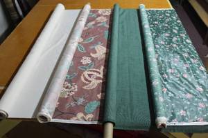 lot 6236 image: This Lot Contains 4 Rolls of Fabric all 48 Including U.S.A Margin Designs Green Sheen Floral Print,  Solid Green Linen Look, Solid White Linen Look, and Floral Paisley