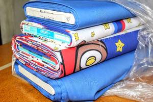 lot 6238 image: This Lot Contains (4) Bolts of Fabric, (2) Coordinating Blues and (2) Super Mario Bros. Print Fabric