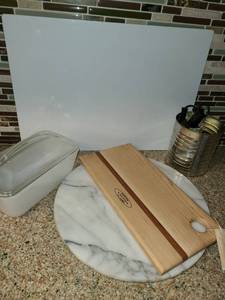 lot 1023 image: Miscellaneous Kitchen Items. Bake Dish with Lid, Wooden Cutting Board, Glass Cutting Board, and a Granite Cutting Board...Round. And some miscellaneous cords