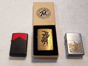 lot 199 image: 3 Vintage Zippo Lighters  Solid Brass wBroncbuster, Black Case Marlboro, and Bird Hunting