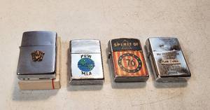 lot 203 image: 4 Vintage Military Themed Lighters  Zippo Navy Crest (box included), Zippo POWMIA, Spirit of 76 ( K Japan) and Zippo USS Constellation
